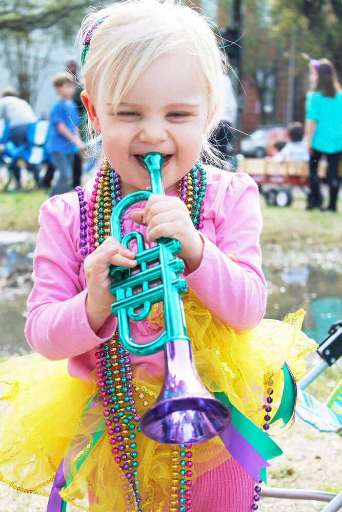 A little girl shows off her Mardi Gras parade catch.